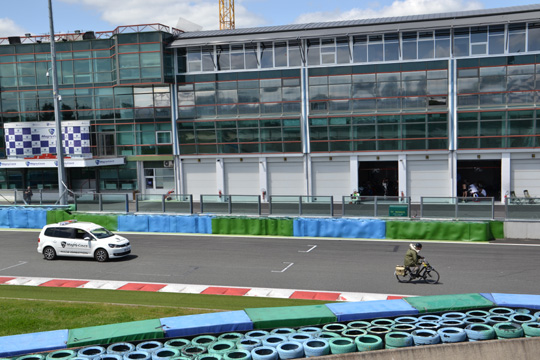 Un participant suivi par une voiture officielle du circuit