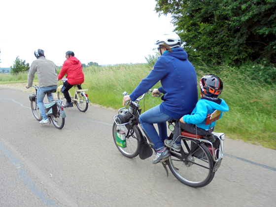 Un enfant bien sage sur un siège bébé sur le solex de sa mère